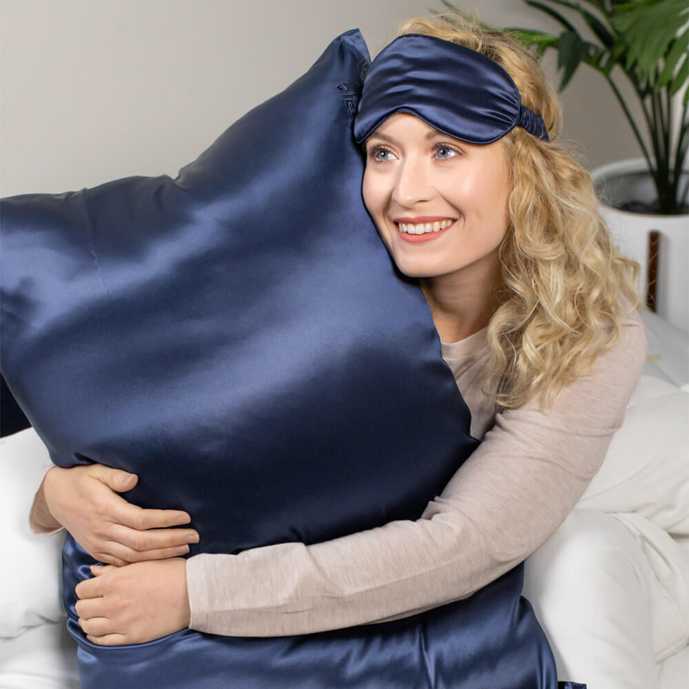 Woman hugging a blue Blissy silk pillowcase